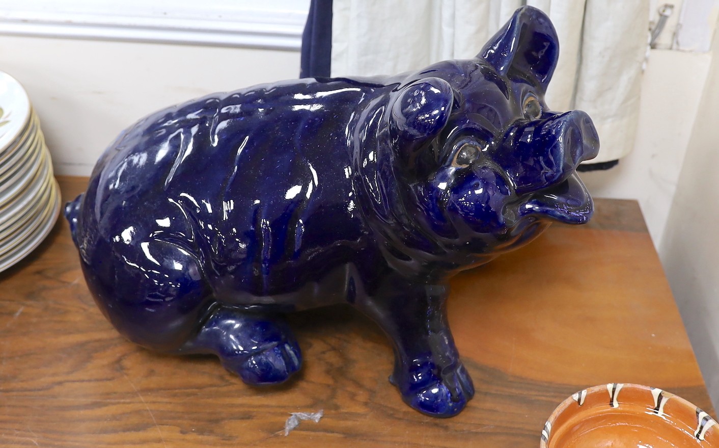 A large seated blue glazed pottery pig, 53cms wide